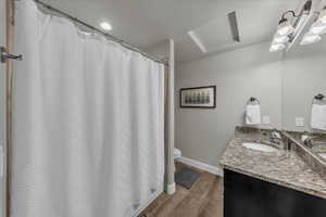 Full bath featuring a shower with shower curtain, vanity, dark wood finished floors, and a textured ceiling