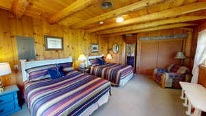 Bedroom featuring electric panel, a wooden ceiling with exposed beams, light carpet, and wood walls