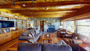 Living room featuring a fireplace, hardwood / wood-style flooring, a wood ceiling with exposed beams, and rail lighting
