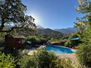 View of swimming pool with patio surround, a mountain view, and a storage shed