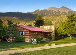 View of front of home featuring a mountain view, a front yard, a metal roof, and a porch