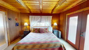 Bedroom featuring french doors, light colored carpet, wooden walls, and wood ceiling