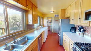 Kitchen featuring tasteful backsplash, independent washer and dryer, light countertops, stainless steel appliances, and light wood finish cabinetry