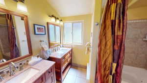 Full bath with two vanities, shower / tub combo with curtain, and light tile patterned floors