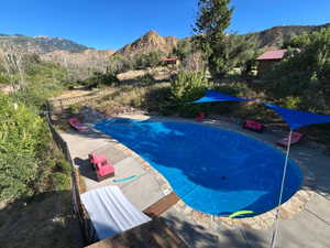 View of swimming pool featuring a mountain view, a fenced backyard, and patio surround