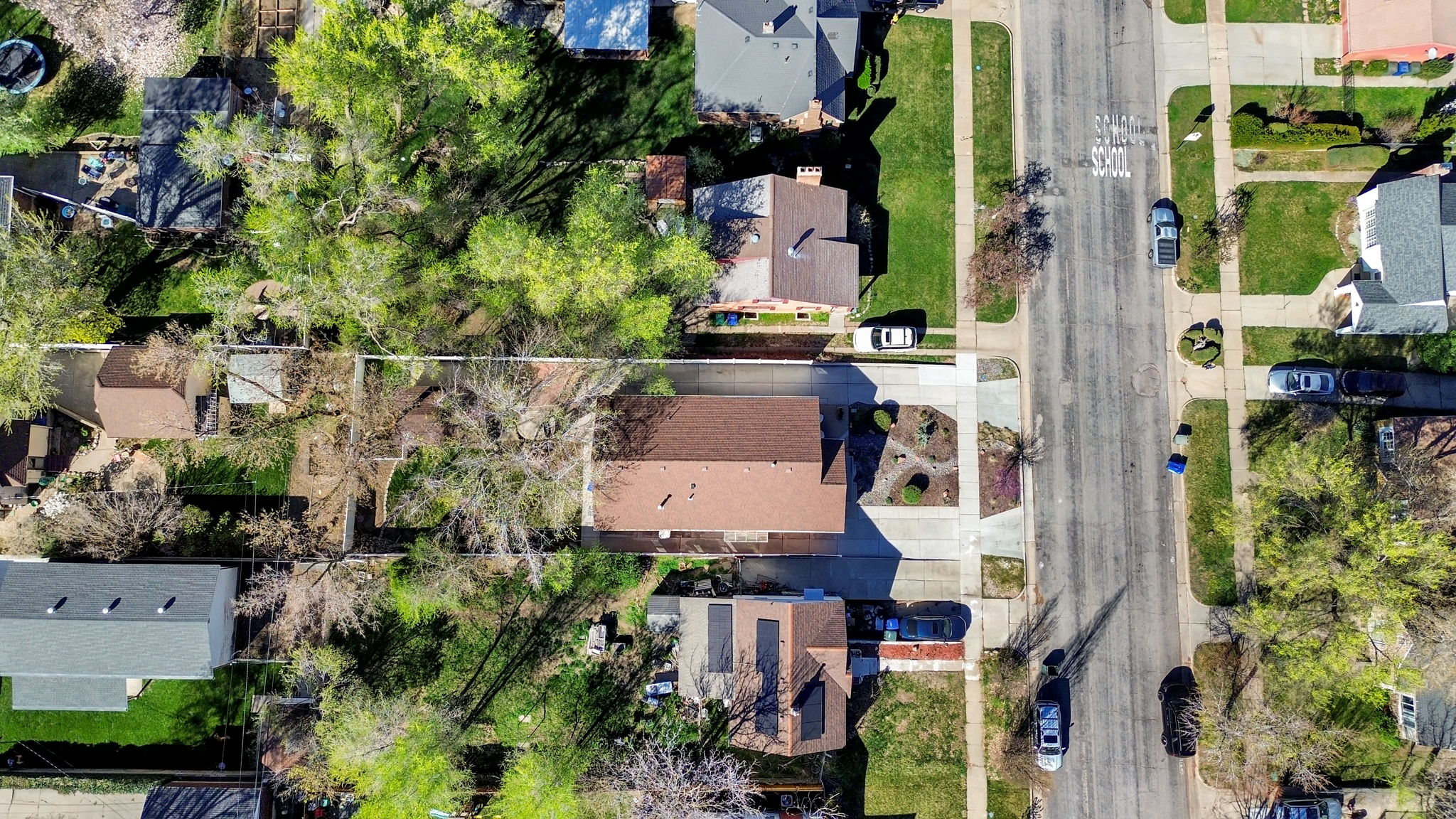 Aerial view of the home showing two driveways, xeriscaped front lawn, and mature trees