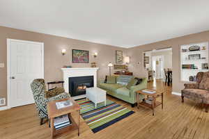 Living room with a gas log fireplace, original wood wood floors, abundant light, and high ceilings