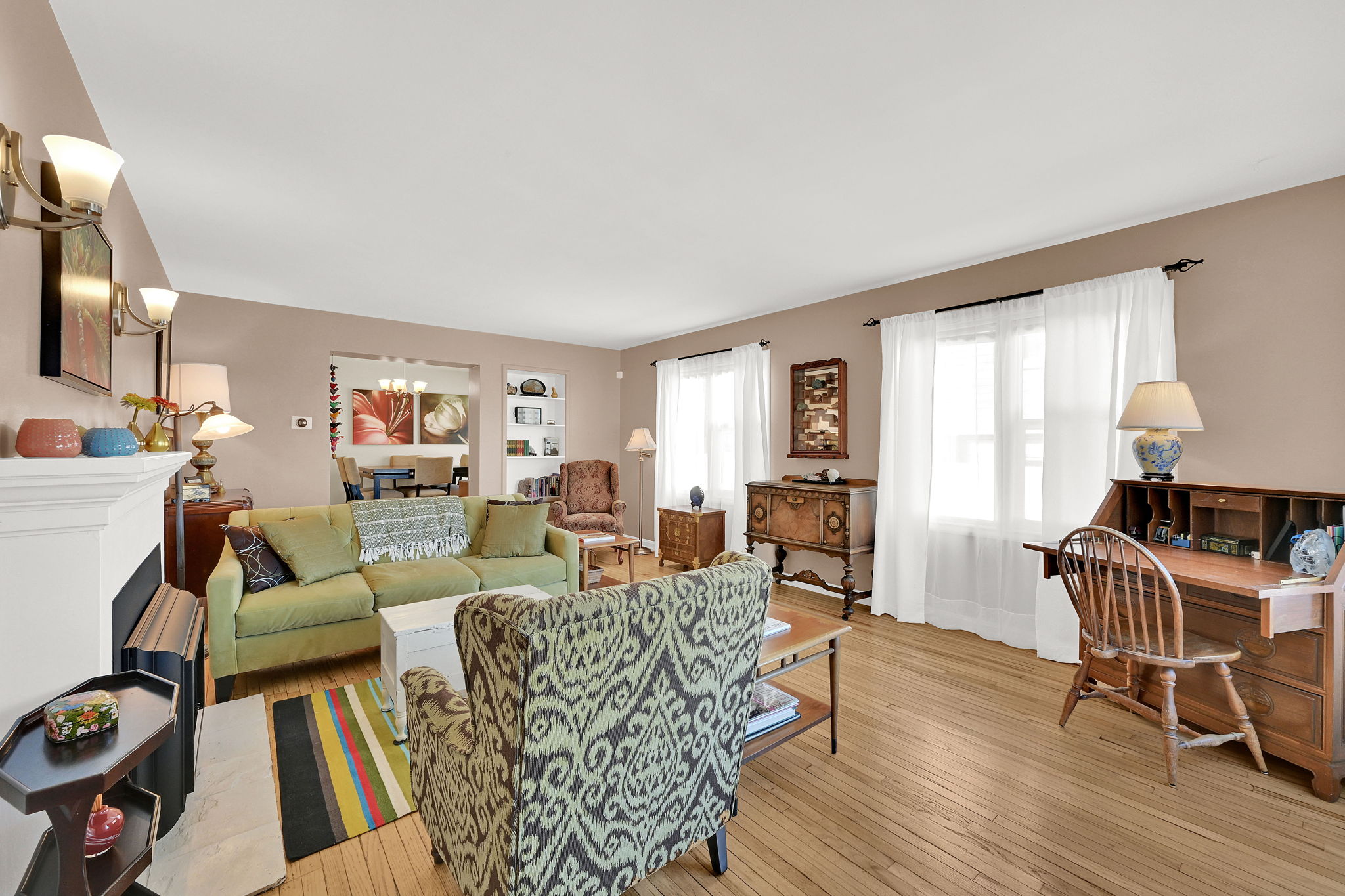 Living room with a gas log fireplace, original wood wood floors, abundant light, and high ceilings
