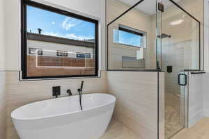 Full bathroom with a freestanding tub, a shower stall, and tile walls