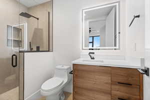 Full bath featuring a stall shower, vanity, and ceiling fan