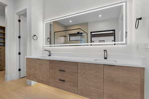 Full bath featuring double vanity, a shower stall, and a walk in closet