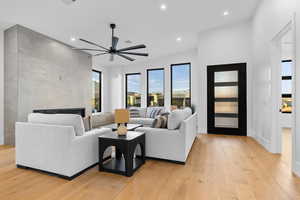 Living room with a tile fireplace, light wood-style flooring, recessed lighting, and ceiling fan
