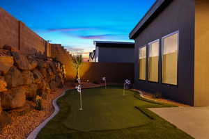 Fenced backyard featuring a putting area