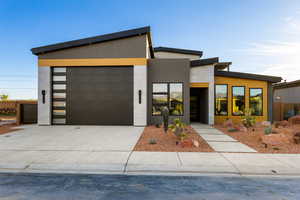Contemporary house featuring an attached garage, driveway, and stucco siding