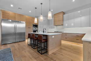 Dual tone kitchen with modern cabinets, a kitchen bar, built in appliances, dual tone cabinetry, and a kitchen island with sink