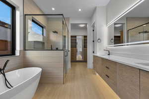Bathroom featuring a spacious closet, a stall shower, a freestanding tub, double vanity, and tile walls