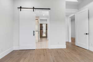 Unfurnished bedroom featuring a barn door and light wood-style flooring