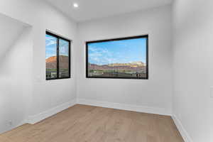 Empty room featuring a mountain view, light wood-type flooring, and recessed lighting