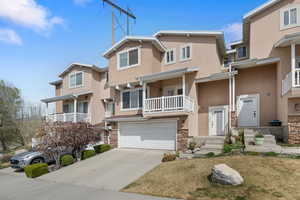 Traditional home featuring a balcony, stone siding, driveway, and stucco siding