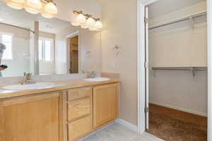 Full bath with a spacious closet, double vanity, a textured ceiling, a shower, and light carpet
