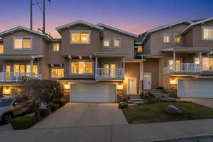 Traditional home featuring a balcony, a garage, stone siding, and driveway
