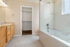 Bathroom with vanity, a combined bath / shower with jetted tub, and a walk in closet