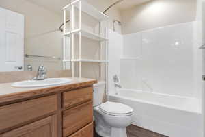 Full bathroom featuring vanity, washtub / shower combination, and dark wood-style flooring