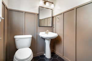 Bathroom featuring a decorative wall and dark tile patterned flooring