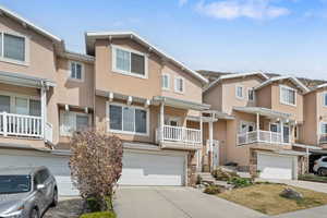 Traditional-style home featuring stone siding, a balcony, a residential view, stucco siding, and driveway