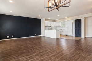 Unfurnished living room with dark wood-style flooring and suspended lighting