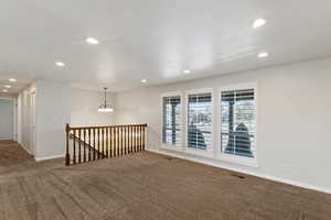 Empty room featuring dark carpet and a chandelier