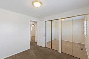 Unfurnished bedroom featuring two closets and dark carpet
