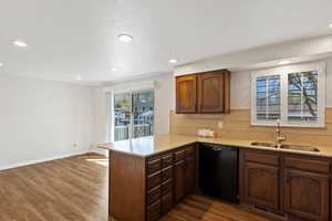 Kitchen with tasteful backsplash, light stone countertops, black dishwasher, dark wood finished floors, and recessed lighting