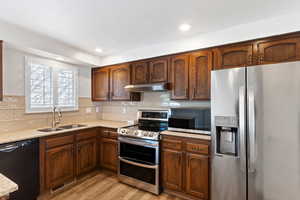 Kitchen featuring stainless steel appliances, light wood finished floors, light stone countertops, backsplash, and recessed lighting