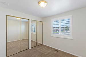 Unfurnished bedroom with two closets and carpet flooring