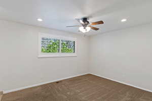 Empty room featuring a ceiling fan, dark colored carpet, and recessed lighting