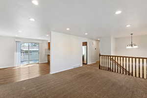Unfurnished room with dark colored carpet and suspended lighting