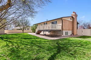 Rear view of property with a gate, a fenced backyard, a chimney, and a wooden deck