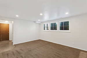 Unfurnished room with dark colored carpet and recessed lighting