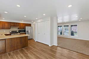 Kitchen featuring stainless steel appliances, recessed lighting, light stone countertops, tasteful backsplash, and a peninsula