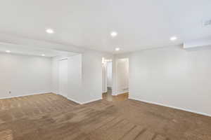 Empty room with dark colored carpet and recessed lighting