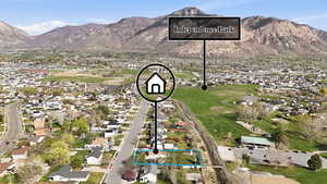 Aerial view of residential area featuring property boundaries highlighted and a mountainous background