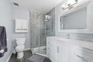 Full bath with vanity, a stall shower, and wood finish floors