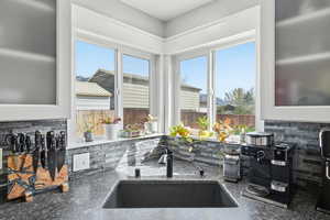 Kitchen view of decorative backsplash, dark stone countertops, and glass insert cabinets