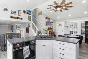 Kitchen with light wood finished floors, oven, dark countertops, a ceiling fan, and recessed lighting