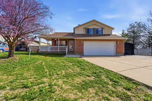View of front of house with covered porch, driveway, a garage, brick siding, and a shingled roof