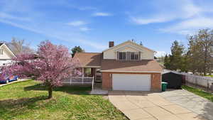 View of front of home featuring a shingled roof, driveway, a front yard, a garage, and brick siding