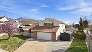 View of front facade with driveway, brick siding, roof with shingles, and a mountain view