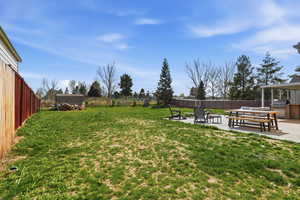Fenced backyard with a patio area, an outdoor kitchen, and an outdoor fire pit