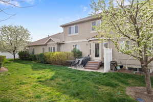 Rear view of house featuring a patio area, a yard, and stucco siding